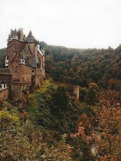 an old castle on top of a hill surrounded by trees