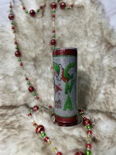 a red and silver christmas candle on a white fur covered surface with beads around it