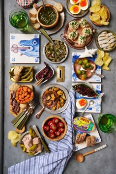 an assortment of food is laid out on a table with dishes and utensils