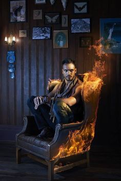 a man sitting on top of a chair covered in fire