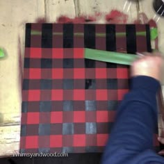 the person is using a green object to cut out pieces of fabric on the floor