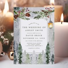 the wedding stationery is surrounded by candles and evergreen branches, which are adorned with pine cones