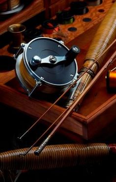 an assortment of fishing rods and reels on a wooden box with other items in the background