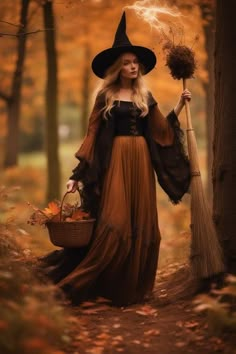 a woman dressed in a witch costume holding a broom and a wicker basket while standing next to a tree