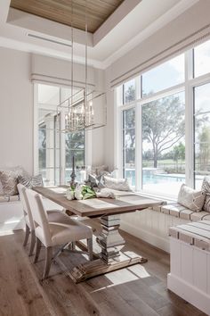 the dining room table is surrounded by white chairs and pillows, along with a large window seat