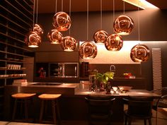 a kitchen filled with lots of lights hanging from it's ceiling above a dining room table