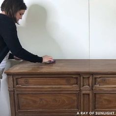 a woman standing on top of a wooden dresser