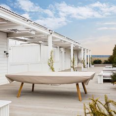 a boat shaped table sitting on top of a wooden floor next to a white building