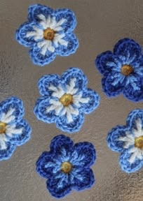 four crocheted blue and white flowers sitting on top of a metal countertop