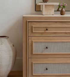 a wooden dresser with two vases and a mirror on the wall behind it in a room