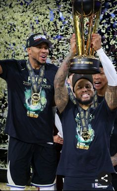 two men holding up a trophy in front of confetti