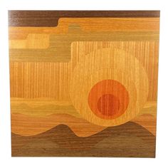 a wooden cutting board with an orange circle in the center and waves on it's surface