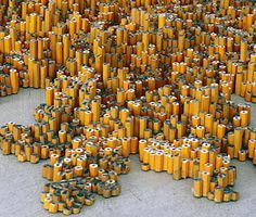 a large group of yellow cans stacked on top of each other with eyes drawn on them