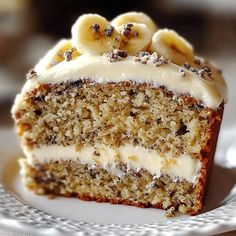 a piece of cake on a plate with white frosting and banana slices in the middle