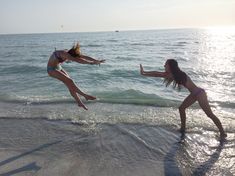 two girls jumping into the water at the beach