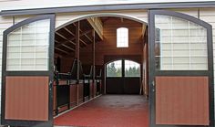 an open horse barn door with horses in the stalls