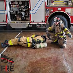 a fireman kneeling down next to a fire truck