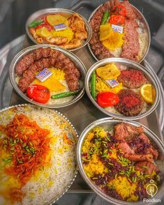 several trays filled with different types of food on top of a metal countertop