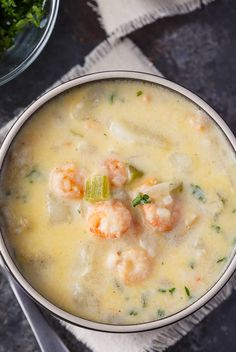 a bowl of soup with shrimp and celery on the side next to a spoon