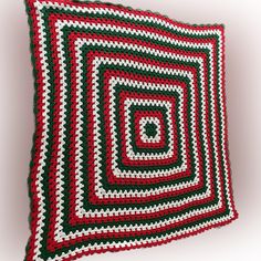 a crocheted square pillow made with red, green and white granny's squares