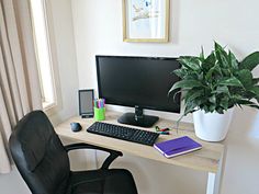 a computer desk with a keyboard, mouse and monitor on it next to a potted plant