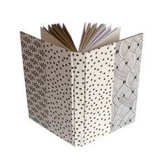 an open book with black and white designs on the pages, sitting in front of a white background