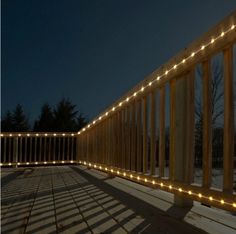 a wooden deck with lights on it and snow in the foreground, at night