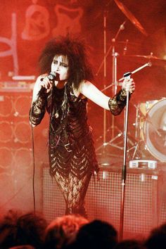 a woman on stage holding a microphone in front of an audience at a rock concert