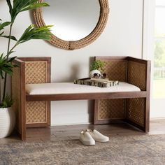 a wooden bench sitting next to a mirror and potted plant on top of a rug