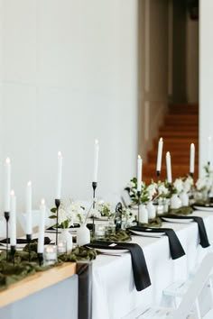 a long table with white flowers and black ribbon on it is set up for an event