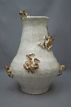 a white vase with some brown and white designs on it's sides, sitting against a gray background