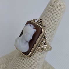 This gorgeous vintage cameo ring is beautifully crafted in a solid 14k gold frame with details at every angle. The victorian style is likely a 1930-1950s creation. In the center is a carved shell cameo of a Roman soldier. The cameo is in excellent condition and the sturdy ring measures approximately 26.45mm tall (including gold filigree fame) x 17.37mm wide. The ring is currently a ring size 7.5 but can be resized by your trusted local jeweler. A bold statement ring for men and women who love an Wedding Rings Photos, Victorian Revival, Beaded Evening Bags, Cameo Ring, Vintage Cameo, Carved Shell, Gold Filigree, Ring For Men, Cool Necklaces