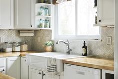 a kitchen with white cabinets and wooden counter tops, including a dishwasher in the center