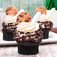 two chocolate cupcakes with white frosting and cookies on top are sitting on a plate