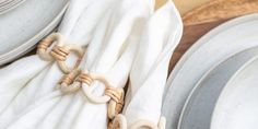 the table is set with plates and napkins, along with an ivory - colored cloth