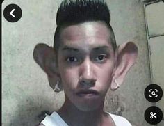 a young man with black hair and piercings on his ears is looking at the camera