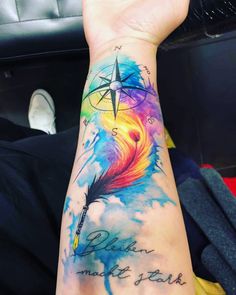 a person's arm with a colorful tattoo on it and a compass in the sky