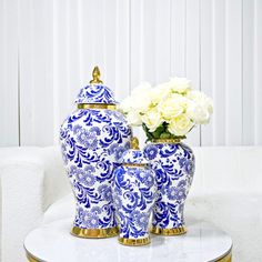 two blue and white vases sitting on top of a table with flowers in them