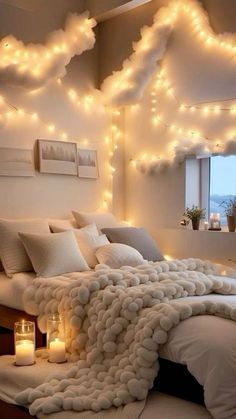 a bedroom with lights on the ceiling and a bed covered in fluffy white blankets, pillows and throws