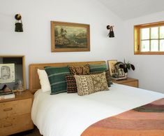 a bedroom with a bed, dresser and two pictures on the wall above it's headboard