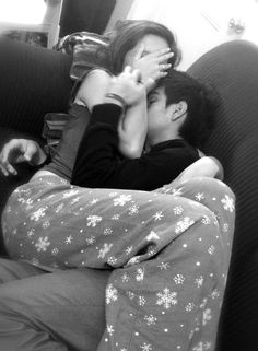 a man and woman laying on top of a couch with their arms around each other