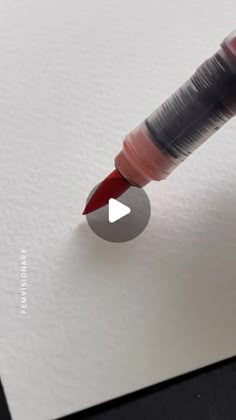 a close up of a red and black pen on top of a white piece of paper