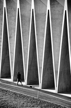 black and white photograph of a person walking by a wall