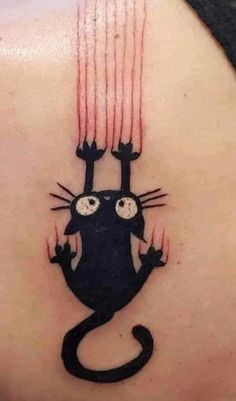 a cat tattoo on the back of a woman's shoulder, with red streaks coming out of it