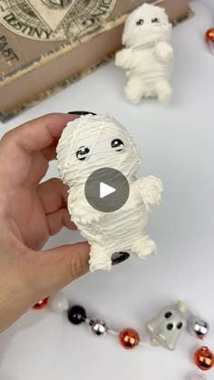 a person holding a small white dog made out of toilet paper and other decorations on a table