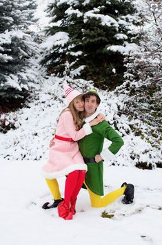 a man and woman in elf costumes posing for a photo on the snow covered ground