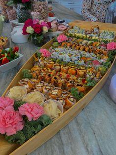 a long boat filled with lots of food on top of a table next to bowls of fruit