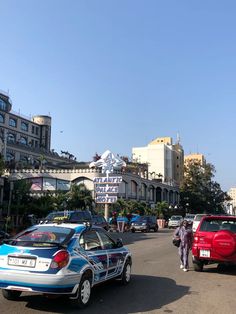 cars are parked on the side of the road in front of buildings and people walking down the street