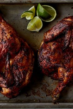 two pieces of meat on a tray with limes