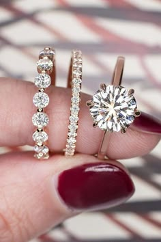 a woman's hand holding three different types of engagement rings and diamond bands on her finger